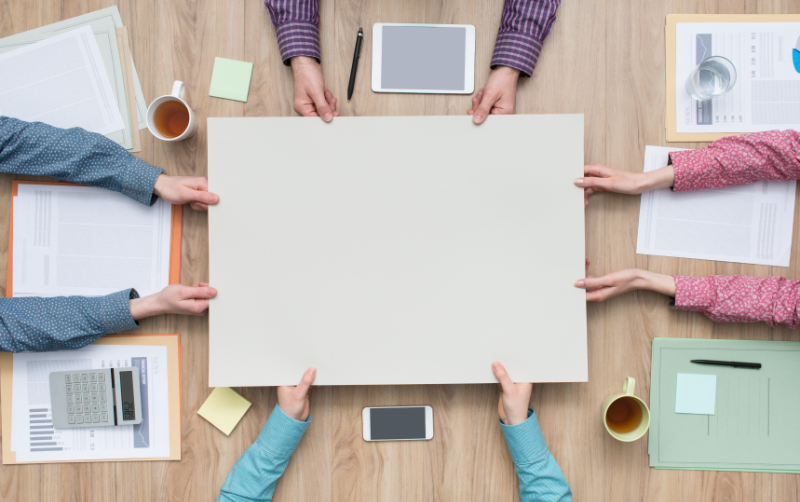 Business team working on a project, they are holding a blank sign together, teamwork and cooperation concept