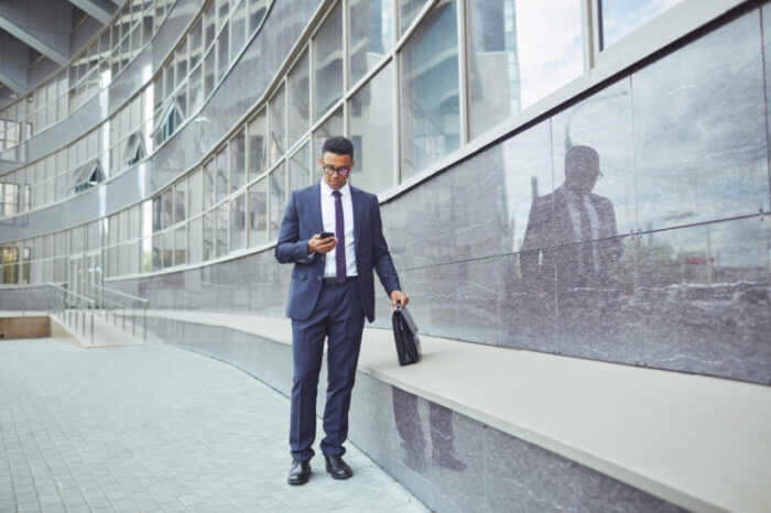 Businessman in suit texting a message outdoors